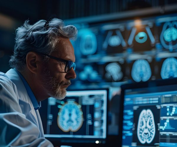 The image depicts a neuroscientist intently observing various brain activity patterns displayed on multiple medical monitors The scene suggests a scientific research setting where the researcher is